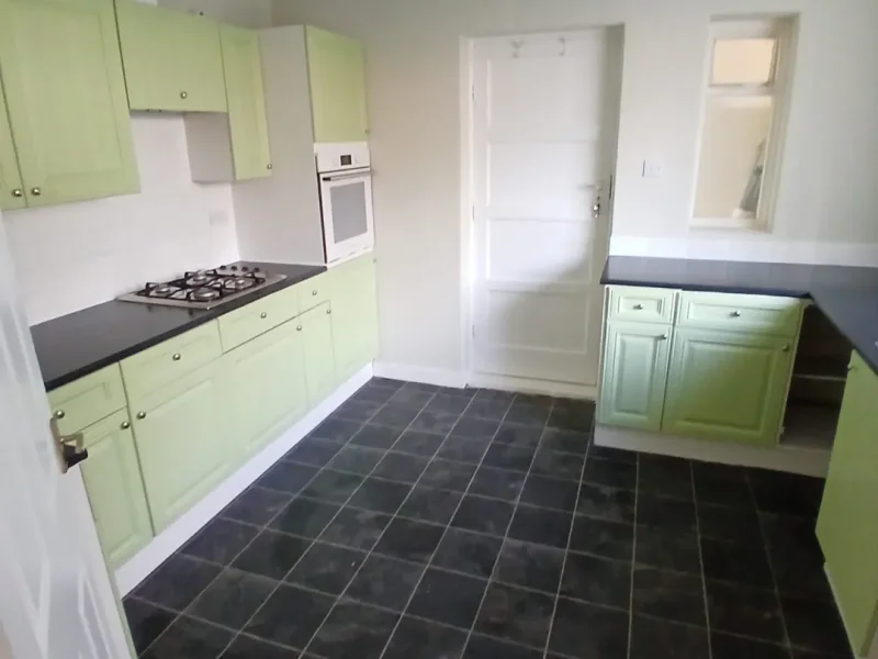 The refreshed kitchen with sage cupboards and dark worktops.