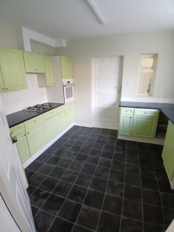 The refreshed kitchen with sage cupboards and dark worktops.