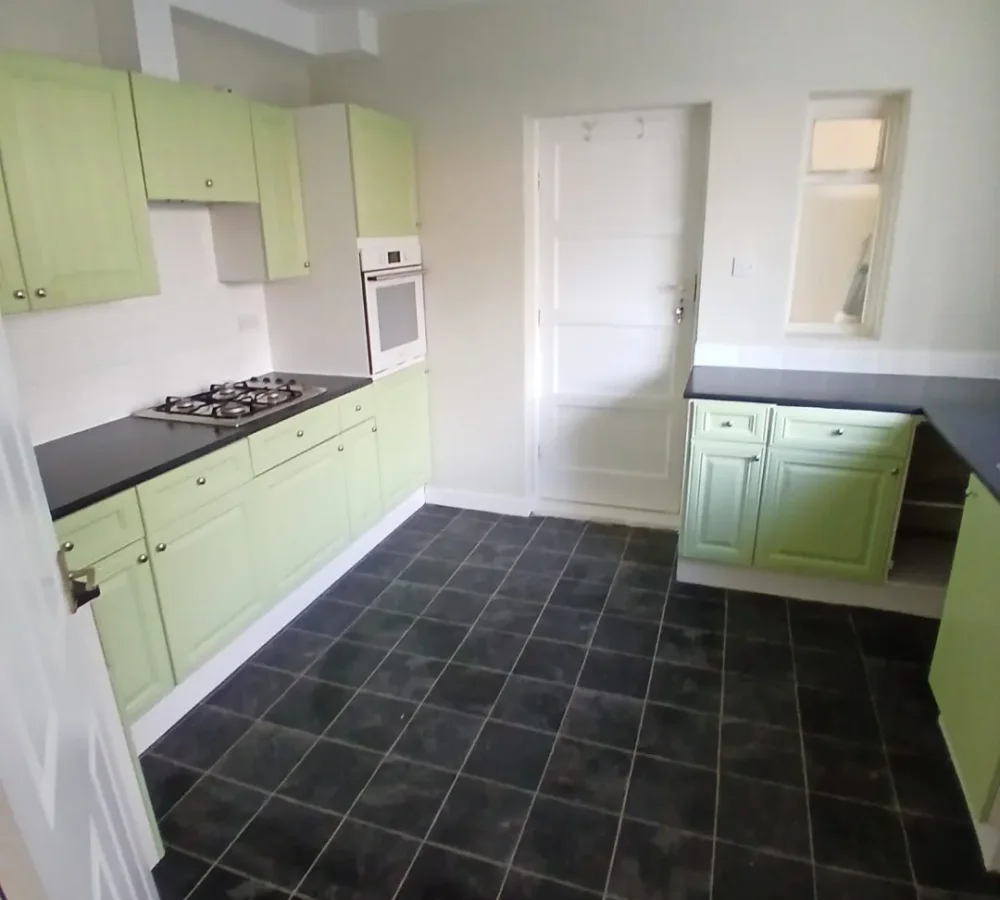 The refreshed kitchen with sage cupboards and dark worktops.
