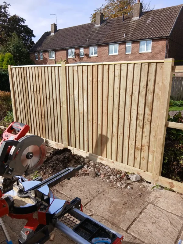 A new timber fence panel being installed between the posts.
