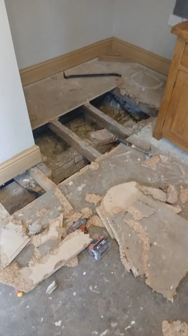 Damaged chipboard being removed to expose the supporting floor joists.