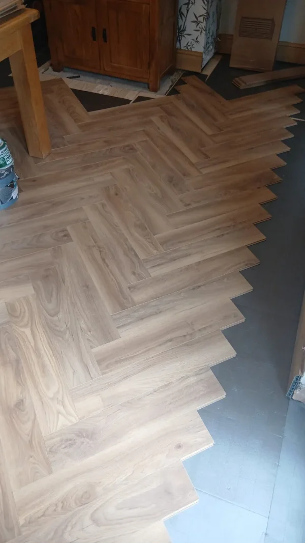 Herringbone laminate installation in progress in the dining area.